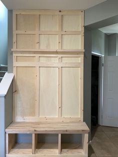 a wooden bench sitting in the middle of a room next to a wall mounted cabinet