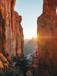 a person standing on the edge of a cliff with mountains in the background at sunset