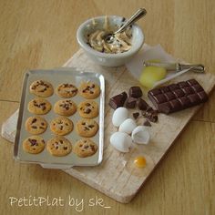 a wooden table topped with chocolate chip cookies and marshmallows next to a bowl of ice cream