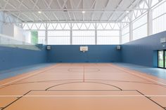 an empty indoor basketball court with blue walls