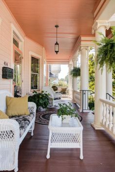 a porch with wicker furniture and potted plants