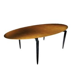 an oval wooden table with black legs and a gold top, on a white background