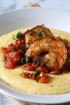 a white plate topped with shrimp and grits