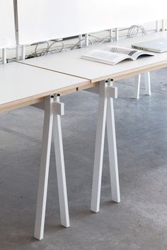 a table with two legs and a keyboard on it, in front of a white wall