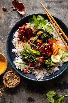 a plate filled with rice, meat and veggies next to chopsticks