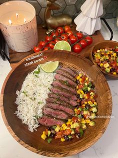 a wooden plate topped with meat, rice and veggies next to a candle