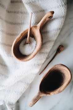 two wooden spoons filled with sugar on top of a white towel next to each other