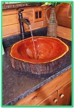 a wooden bowl sink on top of a counter next to a faucet and soap dispenser