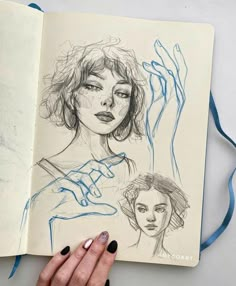 a woman's hand is holding an open book with drawings on it and the pages are drawn