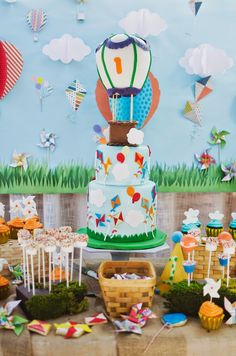 a colorful birthday cake surrounded by cupcakes and decorations