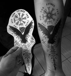 two people with tattoos on their legs and one is holding a paper bird shaped object