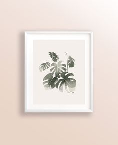 a black and white print with green leaves on a beige background in a white frame