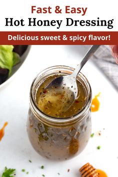 a spoon in a jar filled with hot honey dressing on top of a white table