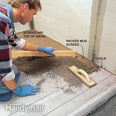 a man working on the side of a building with cement and wood flooring around it