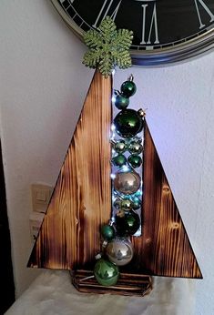 a christmas tree made out of wood with ornaments on it and a clock in the background