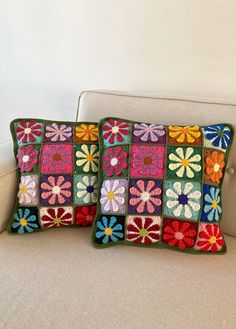 two crocheted pillows sitting on top of a couch