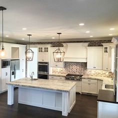 a large kitchen with white cabinets and an island in front of a stove top oven