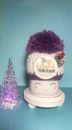 a purple and white hat sitting on top of a table next to a small christmas tree