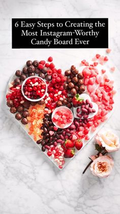 a heart - shaped bowl filled with candy and nuts on top of a marble table