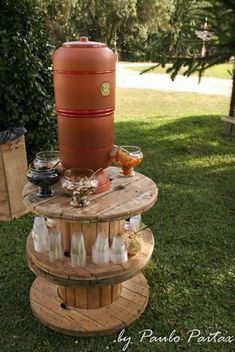 an outdoor table made out of pallet wood with bottles on it and a large barrel in the middle