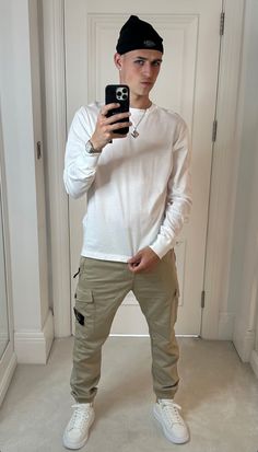 a young man taking a selfie in front of a mirror wearing khaki pants