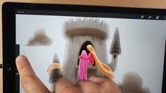 a person holding up a small doll in front of a computer screen with an image of a castle on it