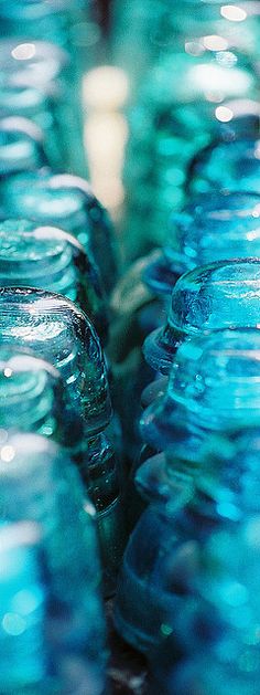 many glass jars are stacked on top of each other in blue and green hues