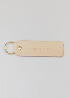 a keychain with the words windy city on it and a gold plated metal hook