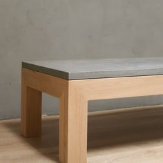 a wooden bench sitting on top of a hard wood floor next to a gray wall