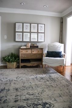 a living room with a rug, chair and pictures on the wall