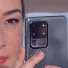 a close up of a person holding a cell phone in front of their face and looking at the camera