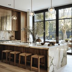 a large kitchen with marble counter tops and wooden cabinetry, along with stools