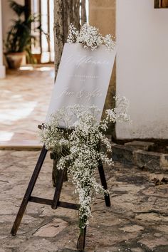 a sign that has some flowers on it and is next to an easel with a sign