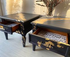 two black and gold painted tables sitting on top of a hard wood floor next to a vase with flowers