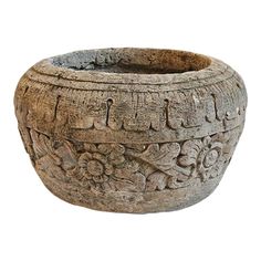 an old wooden bowl with carvings on the sides and flowers in the middle, sitting on a white surface