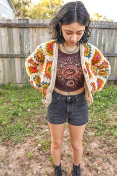 a woman standing in front of a fence wearing short shorts and a cropped top