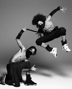 two shirtless men in black and white posing for a photo with one man jumping