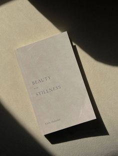 a white book sitting on top of a table next to a shadow from the sun