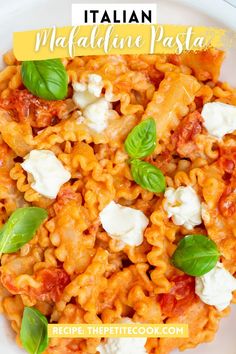 pasta with tomato sauce, cheese and basil leaves in a white bowl on top of a wooden table