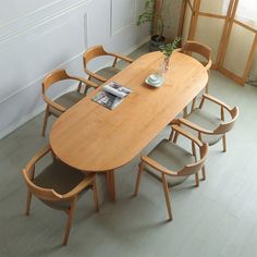 a wooden table with six chairs around it and a vase filled with flowers on top