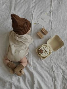 a baby is sitting on the bed next to some items that are in their boxes