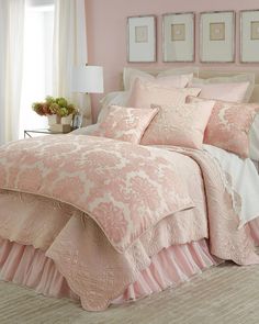 a bed with pink comforter and pillows in a room