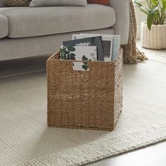 a wicker basket with magazines in it sits on the floor next to a couch