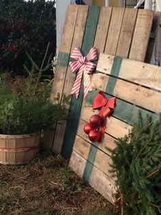 a wooden pallet with christmas decorations on it and a bow hanging from the side