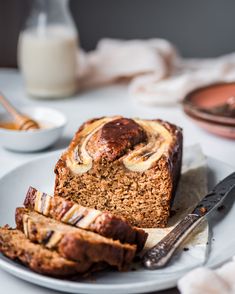 a loaf of banana bread sitting on top of a white plate next to sliced bananas