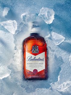 a bottle of ballantine's is sitting in the snow with ice around it