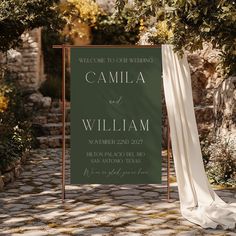 a welcome sign for a wedding in front of a stone path with trees and greenery