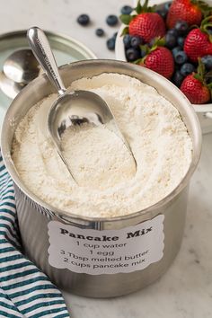 there is a spoon in a can of ice cream next to some strawberries