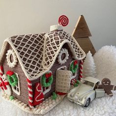 a crocheted house with a car parked next to it on a white surface