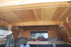 the inside of a small wooden cabin with clothes hanging from it's ceiling and shoes on the floor